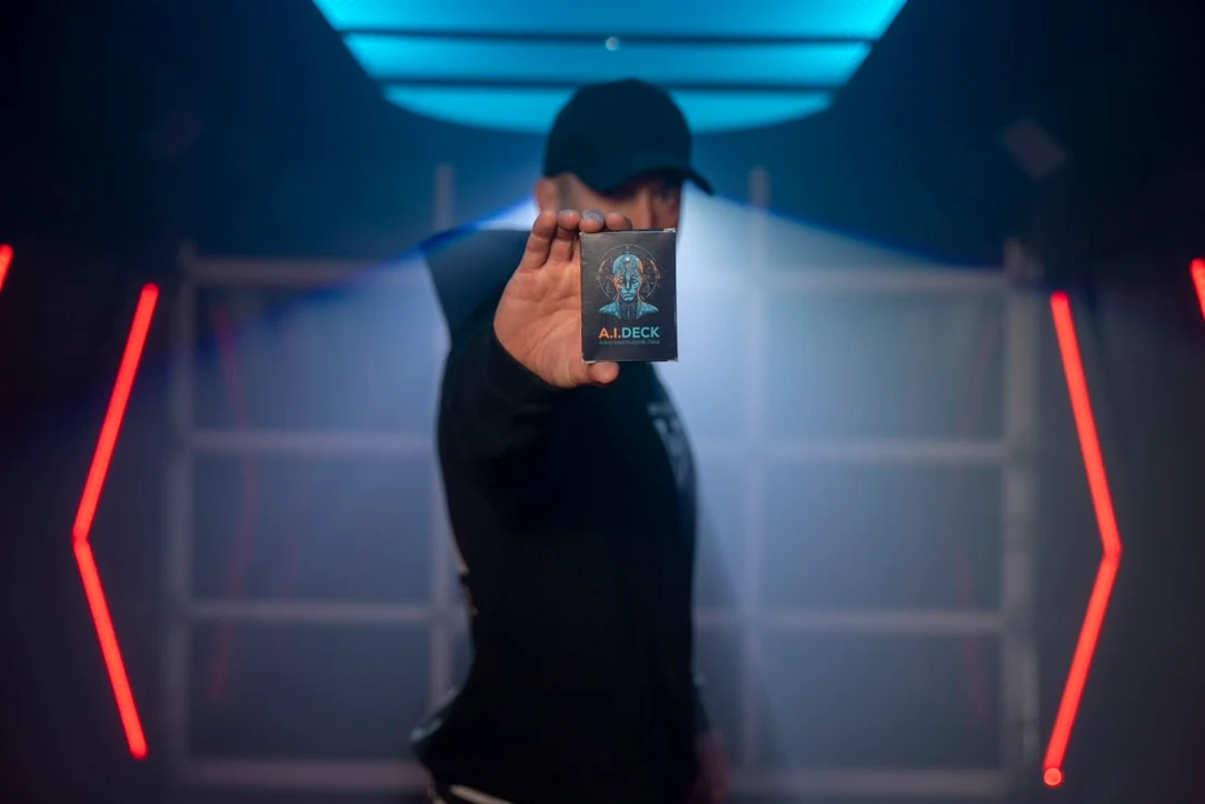 Performer in a stage-lit room holding up the A.I. Deck box toward the camera.